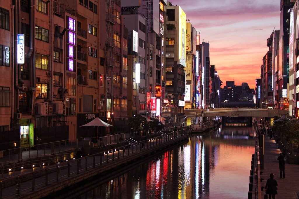 Akşam ışıklarıyla aydınlanan Osaka Dotonbori kanalı ve kalabalık yaya caddesi