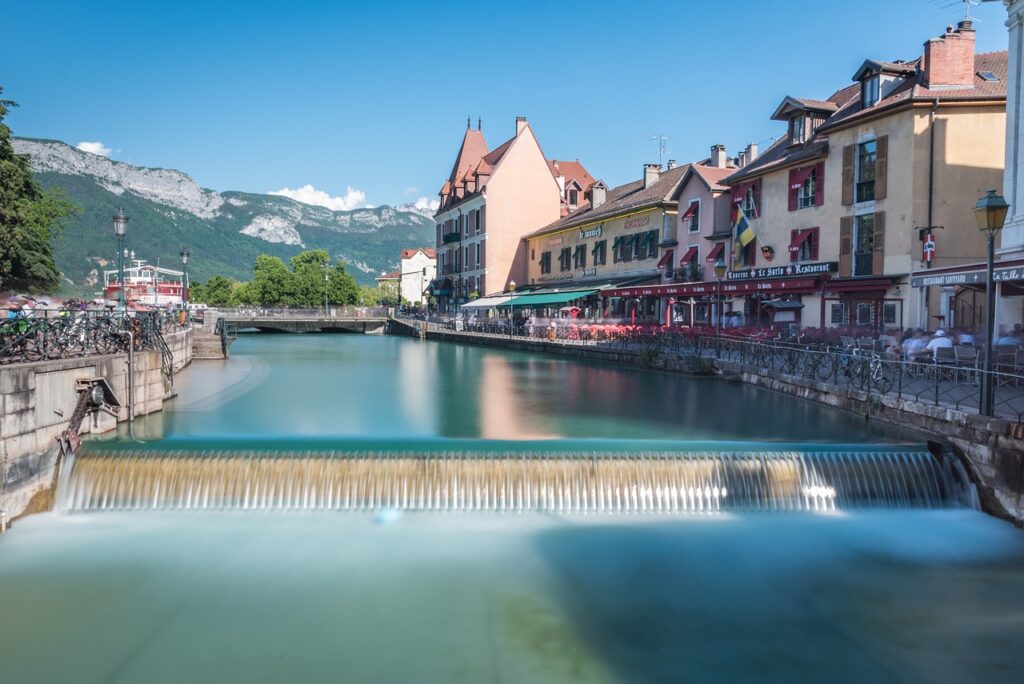 Annecy'de Thiou kanalı ve arkasındaki dağ manzarası