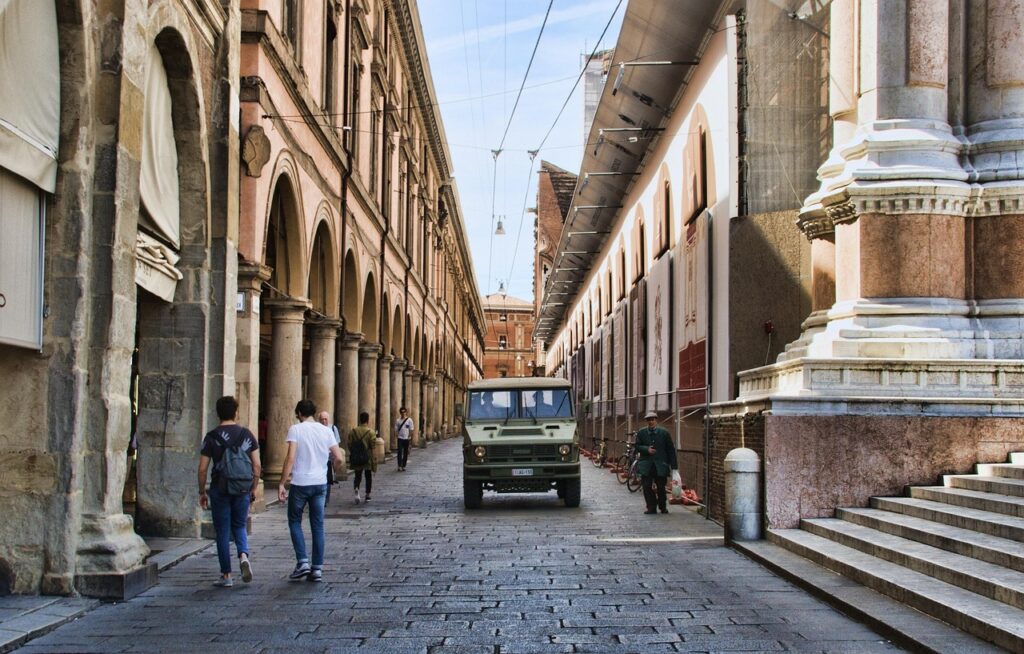 Bologna'da kemerli kaldırımların altında yürüyen insanlar