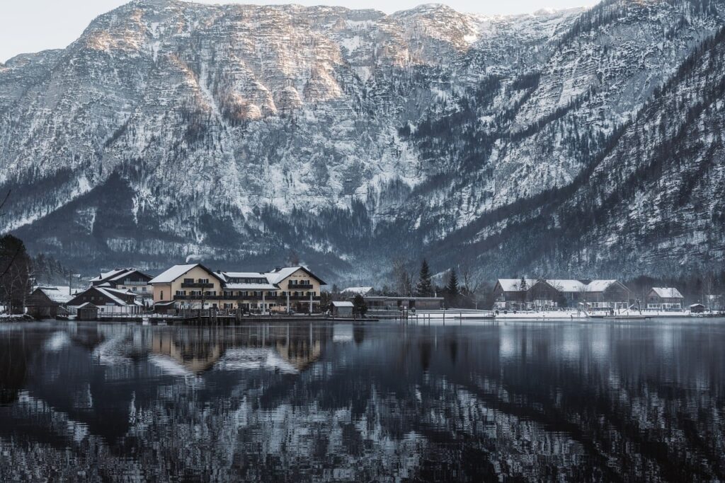 Karla kaplı dağların arasında Hallstatt gölü ve köy manzarası