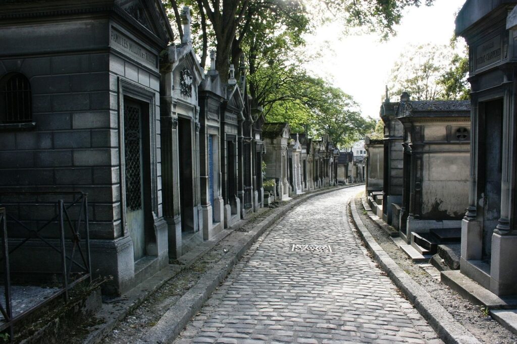 Paris Père Lachaise Mezarlığı'nda ağaçlar arasındaki eski mezar taşları