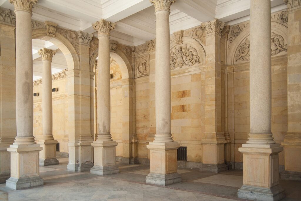 Karlovy Vary'de kemerli kolonadların altında yürüyen ziyaretçiler