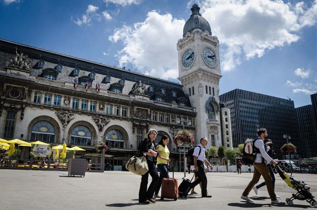 Paris'te büyük bir istasyonun peronunda hazır bekleyen tren ve valizli yolcular