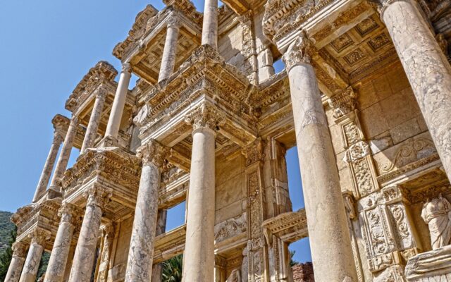 Ailesiyle tarihi bir yerde gezen çocuk, arka planda antik taş kalıntılar