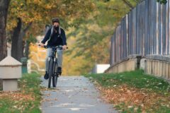 Nehir kenarındaki bisiklet yolunda pedal çeviren bir gezgin