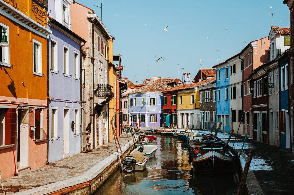 Burano adasında kanal kenarına dizilmiş sarı, pembe ve mavi boyalı evler