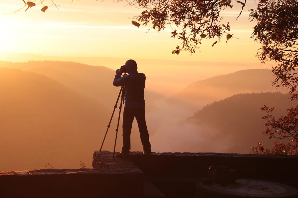 Kayalık bir seyir noktasında gün batımında duran tripod