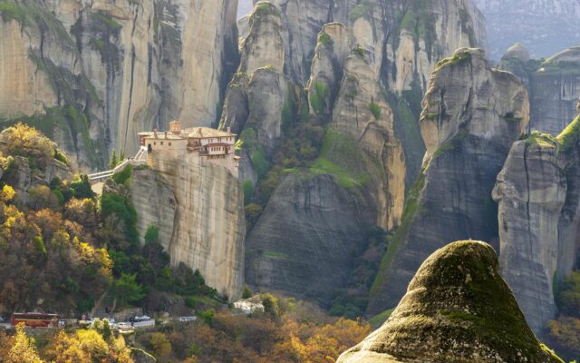 Yunanistan'ın Meteora bölgesinde dik kayalıkların üstüne kurulmuş manastırlar ve sisli vadi manzarası