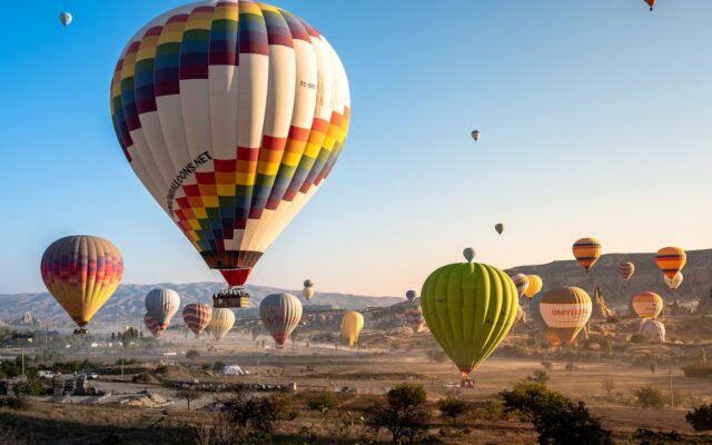 Kapadokya'da gündoğumunda gökyüzünde uçan sıcak hava balonları