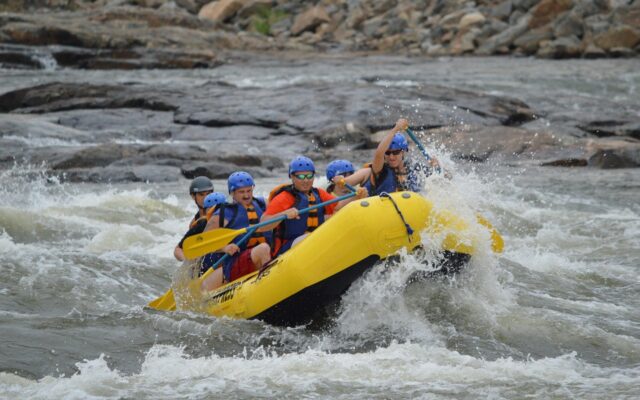 Akarsuda rafting botuyla rapidlerden geçen bir grup gezgin