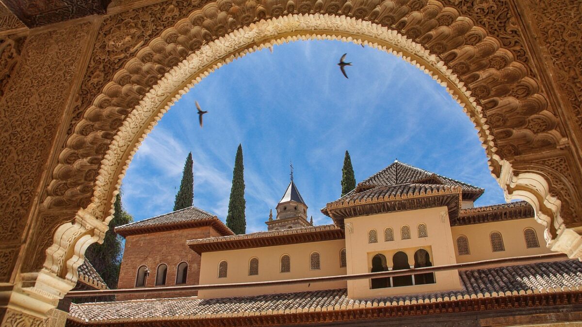 Granada'daki Alhambra sarayının günbatımında görünümü ve çevresindeki yeşil tepeler