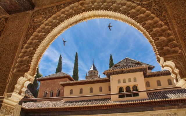 Granada'daki Alhambra sarayının günbatımında görünümü ve çevresindeki yeşil tepeler
