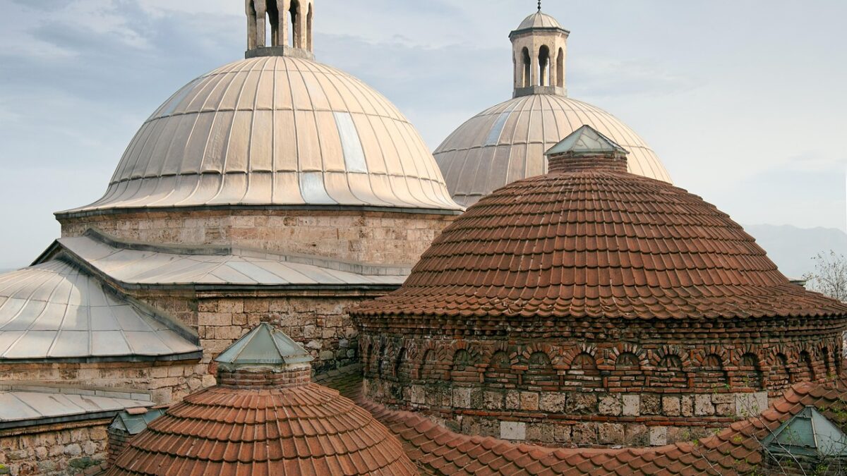 Kubbeli pencerelerden süzülen ışığın aydınlattığı tarihi bir Türk hamamının iç mekânı