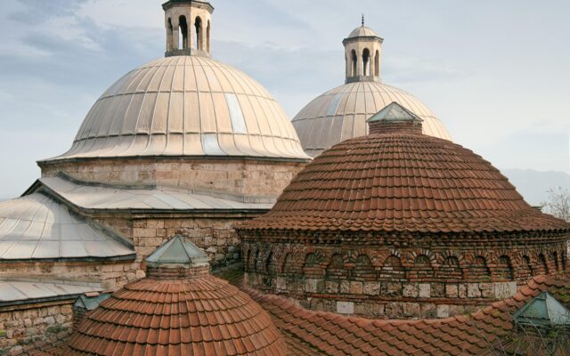 Kubbeli pencerelerden süzülen ışığın aydınlattığı tarihi bir Türk hamamının iç mekânı