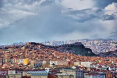 Tepede yükselen tarihi bir kale surları ve çevresindeki şehir manzarası