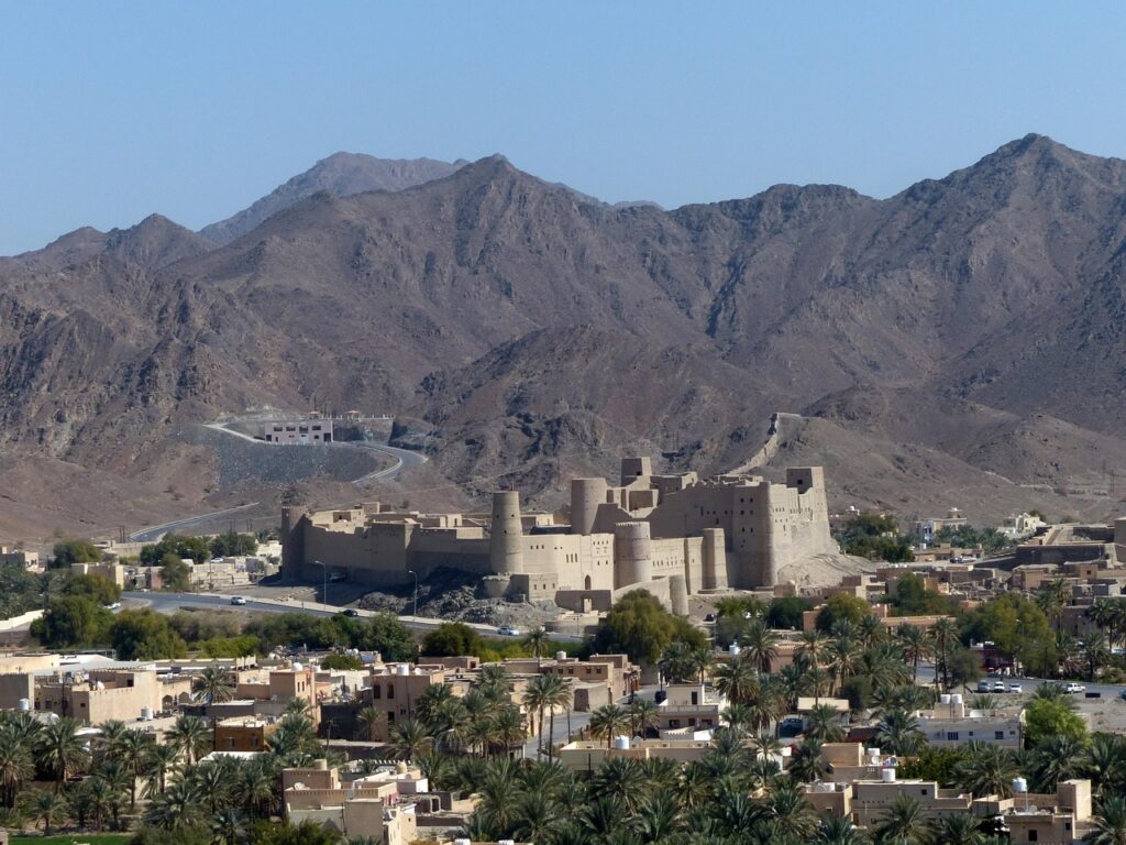 Nizwa Kalesi'nin yuvarlak kulesi ve çevresindeki palmiyeler